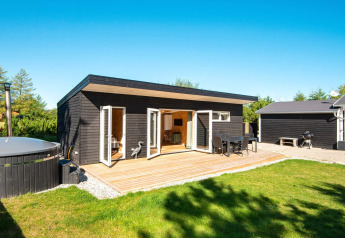 Casa vacanze moderna in legno nero con ampia terrazza e vasca idromassaggio a Glesborg, Danimarca.
