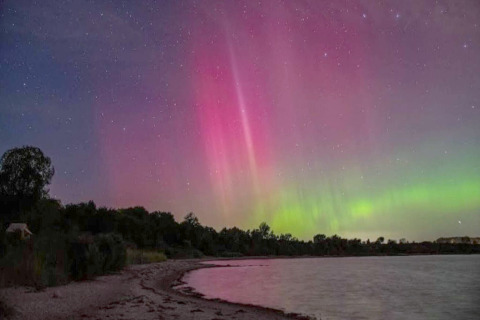 Nordlichter über Strand und Bäumen am „4-Personen-Ferienhaus in Haderslev“, Dänemark, nachts.