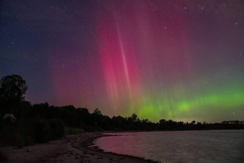 Aurores boréales sur le rivage près du lodge 4 personnes de Haderslev, Danemark, sous le ciel étoilé.
