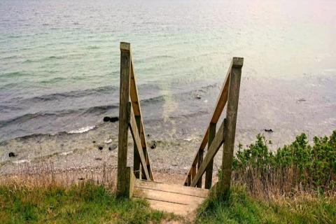 Holztreppe führt zum Strand am Wasser, fotografiert bei einem 4-Personen-Ferienhaus in Haderslev.