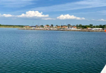 Udsigt over vandet med lystbådehavn og huse i baggrunden nær Haderslev, Danmark, under blå himmel.
