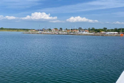 Vue sur l’eau vers un port de plaisance et des maisons à Haderslev, Danemark, sous ciel bleu et nuages.