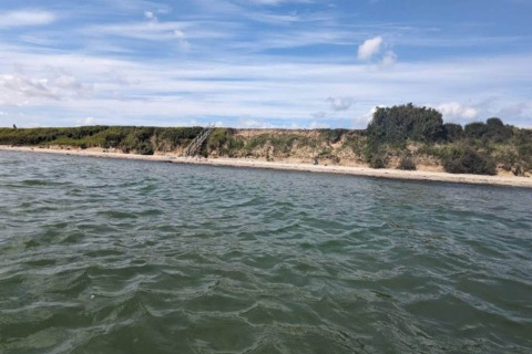 Vue sur l’eau et la plage près du 'gîte pour 4 personnes à Haderslev', Danemark, par une journée ensoleillée.