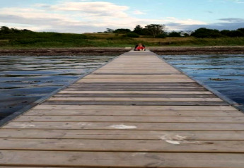 Longue jetée en bois au-dessus de l'eau, personne assise au bout près du 4 person holiday home à Haderslev.