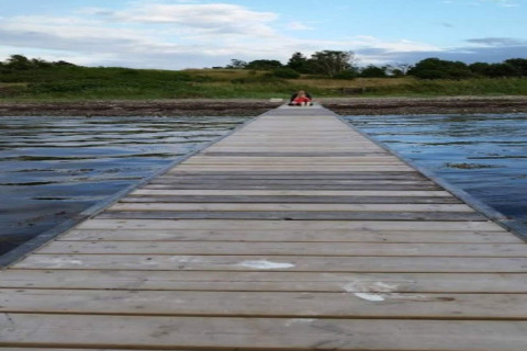 Longue jetée en bois au-dessus de l'eau, personne assise au bout près du 4 person holiday home à Haderslev.