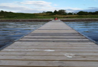 Longue jetée en bois au-dessus de l'eau, personne assise au bout près du 4 person holiday home à Haderslev.