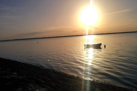 Coucher de soleil sur l’eau au «gîte 4 personnes à Haderslev», Danemark, avec un bateau visible.