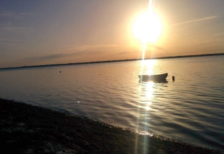 Coucher de soleil sur l’eau au «gîte 4 personnes à Haderslev», Danemark, avec un bateau visible.