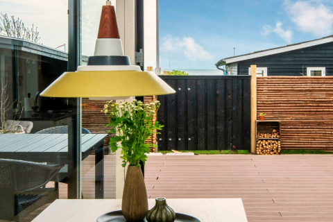 Udsigt gennem et vindue fra feriehjem i Haderslev, Danmark, med moderne indretning og terrasse.
