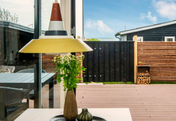 Udsigt gennem et vindue fra feriehjem i Haderslev, Danmark, med moderne indretning og terrasse.