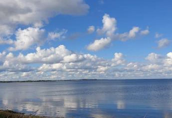 Uitzicht op zee en wolkenlucht vanaf een vakantiehuis in Haderslev, Denemarken, op een zonnige dag.