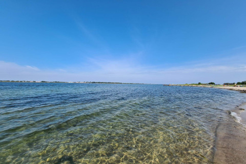 Vue de plage depuis « maison de vacances 4 personnes à Haderslev » au Danemark, eau claire et ciel bleu.