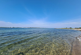 Vue de plage depuis « maison de vacances 4 personnes à Haderslev » au Danemark, eau claire et ciel bleu.