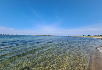 Strandblick vom „4-Personen-Ferienhaus in Haderslev“ in Dänemark, klares Wasser und blauer Himmel.