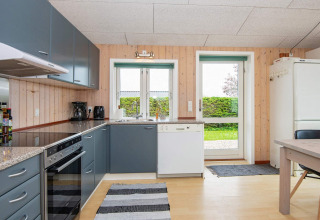 Cuisine moderne d’une maison de vacances à Haderslev, Danemark, avec armoires grises et vue sur le jardin.