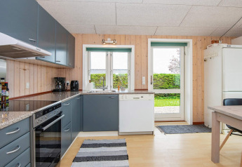 Cocina moderna en una casa de vacaciones en Haderslev, Dinamarca, con gabinetes grises y vista al jardín.