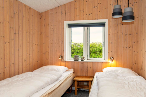 Chambre avec deux lits simples, murs en bois et fenêtre dans une maison de vacances pour 4 à Haderslev, Danemark.