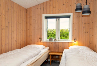 Chambre avec deux lits simples, murs en bois et fenêtre dans une maison de vacances pour 4 à Haderslev, Danemark.