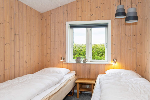 Chambre avec deux lits simples, murs en bois et fenêtre dans une maison de vacances pour 4 à Haderslev, Danemark.