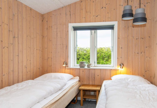 Chambre avec deux lits simples, murs en bois et fenêtre dans une maison de vacances pour 4 à Haderslev, Danemark.