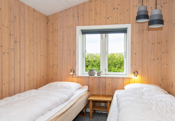 Chambre avec deux lits simples, murs en bois et fenêtre dans une maison de vacances pour 4 à Haderslev, Danemark.