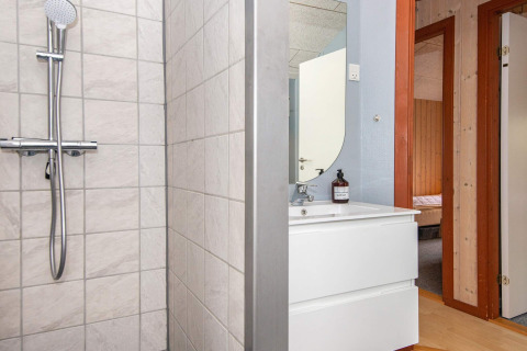 Salle de bain avec douche, lavabo et miroir dans une maison de vacances à Haderslev, Danemark. Porte visible.