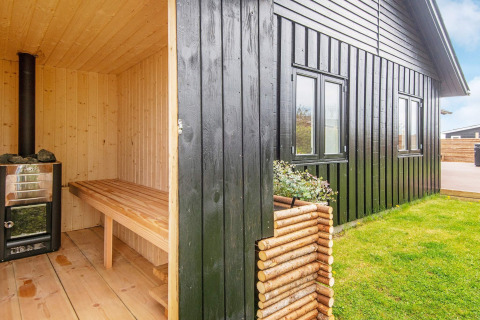 Sauna extérieur en bois à côté d'un gîte noir avec pelouse à Haderslev, au Danemark.
