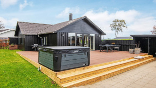 Modernes Ferienhaus in Haderslev mit großer Holzterrasse, Whirlpool, Sitzbereich und Garten.