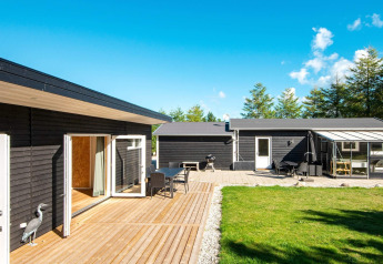 Espace extérieur de la maison de vacances pour 5 personnes à Glesborg, Danemark, avec terrasse en bois et façades noires.
