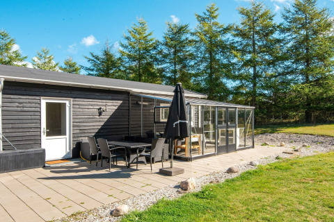 Solrig terrasse med spiseområde og glasoverdækning ved feriehus til 5 personer i Glesborg, Danmark.