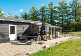 Solrig terrasse med spiseområde og glasoverdækning ved feriehus til 5 personer i Glesborg, Danmark.