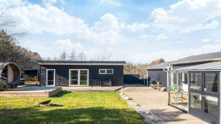 Sort træhus med terrasse, have og moderne udendørs faciliteter på 5-personers feriebolig i Glesborg.