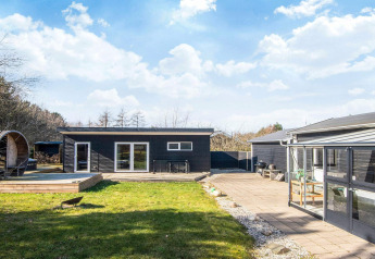 Lodge noire moderne avec terrasse, pelouse et coin repas extérieur pour 5 personnes à Glesborg.