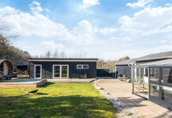 Sort træhus med terrasse, have og moderne udendørs faciliteter på 5-personers feriebolig i Glesborg.