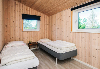 Dormitorio con dos camas individuales y paredes de madera en la casa de vacaciones en Glesborg, Dinamarca.