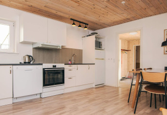 Cuisine moderne et coin repas dans une maison de vacances à Glesborg, Danemark, avec plafond bois.