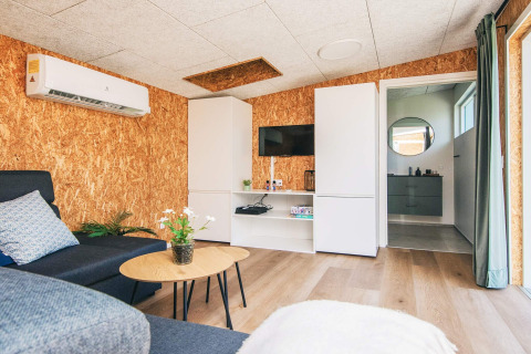 Stue i feriebolig i Glesborg, Danmark, med moderne indretning, aircondition og kig til badeværelse.