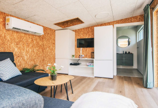Stue i feriebolig i Glesborg, Danmark, med moderne indretning, aircondition og kig til badeværelse.