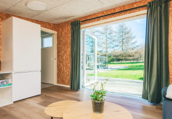 Wohnbereich eines Ferienhauses in Glesborg, Dänemark, mit geöffneten Türen zum Garten und Terrasse.