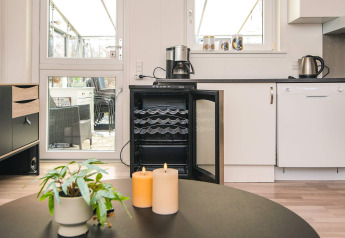 Moderne køkken med åben vinkøler, kaffemaskine, stearinlys og plante i feriebolig i Glesborg, Danmark.
