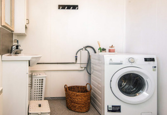 Buanderie dans une maison de vacances à Glesborg, Danemark, avec lave-linge, panier et lavabo.