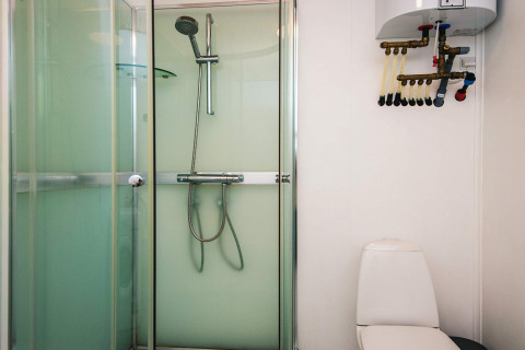 Badeværelse med brusekabine, toilet og varmtvandsbeholder i feriehus for 5 personer i Glesborg, Danmark.