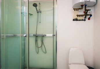 Badeværelse med brusekabine, toilet og varmtvandsbeholder i feriehus for 5 personer i Glesborg, Danmark.