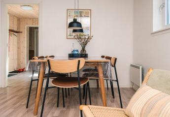 Eethoek in vakantiewoning in Glesborg, Denemarken, met houten stoelen, plastic tafelkleed en Scandinavische stijl.