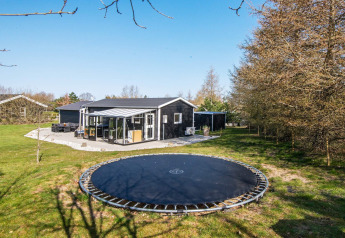 Vue extérieure d'une maison de vacances pour 5 personnes à Glesborg, Danemark, avec un trampoline enterré.
