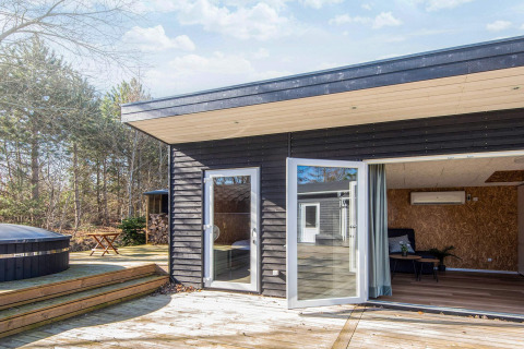 Udendørs terrasse og indgang til 5 personers feriehus i Glesborg, Danmark, omgivet af natur og træer.