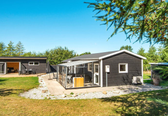 Maison de vacances noire moderne avec véranda et jardin à Glesborg, Danemark, par temps ensoleillé.