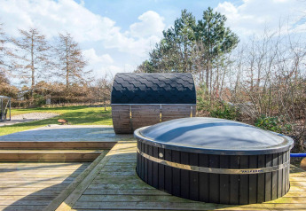 Spa extérieur et sauna sur terrasse en bois à la maison de vacances pour 5 personnes à Glesborg, Danemark.