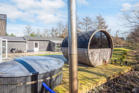 Udendørs terrasse med spabad og tøndesauna ved 5 personers feriehus i Glesborg, Danmark, omgivet af natur.