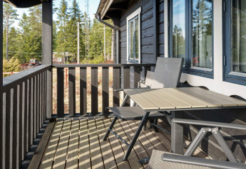 Balcon en bois avec table et chaises d'une maison de vacances pour 6 personnes à Kopparberg, Suède, vue forêt.